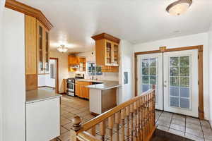 Kitchen with a healthy amount of sunlight, kitchen peninsula, stainless steel range, and french doors