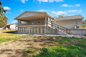 Rear view of property featuring cooling unit, french doors, and a balcony