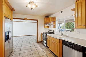 Kitchen with ventilation hood, sink, a textured ceiling, light tile patterned flooring, and stainless steel appliances