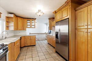 Kitchen with a wealth of natural light, sink, light tile patterned floors, and stainless steel appliances