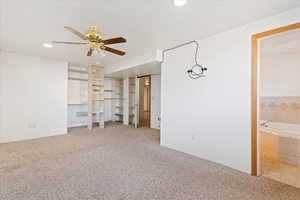 Unfurnished bedroom featuring connected bathroom, ceiling fan, and carpet floors