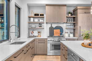 Kitchen featuring light stone countertops, sink, light wood-type flooring, and appliances with stainless steel finishes