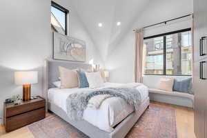 Bedroom featuring multiple windows, light hardwood / wood-style flooring, and high vaulted ceiling