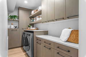 Washroom featuring separate washer and dryer, cabinets, and light wood-type flooring