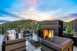 Deck at dusk with an outdoor living space with a fireplace and a mountain view