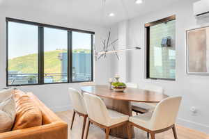 Dining space featuring a wall mounted air conditioner, a chandelier, and light hardwood / wood-style flooring