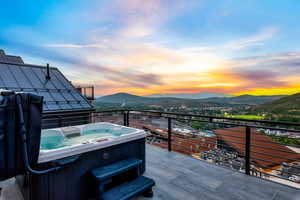 Deck at dusk with a mountain view and a hot tub