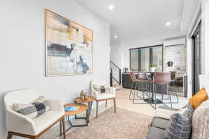 Living room featuring beverage cooler, light colored carpet, a wall unit AC, and bar area