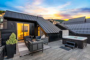 Patio terrace at dusk with outdoor lounge area and a hot tub