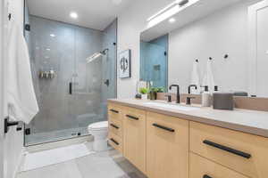 Bathroom with tile patterned floors, vanity, toilet, and walk in shower