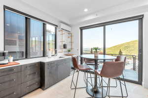 Kitchen with dark brown cabinetry, sink, light tile patterned floors, and an AC wall unit