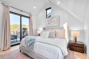 Bedroom featuring access to exterior, vaulted ceiling, and light wood-type flooring