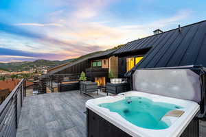 Deck at dusk featuring a mountain view and a hot tub