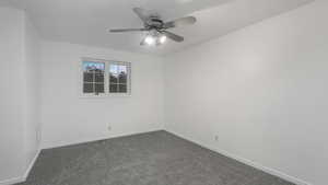 Empty room with ceiling fan and dark carpet