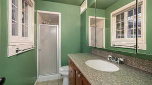 Bathroom featuring tile patterned flooring, vanity, toilet, and a shower with shower door