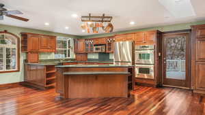 Kitchen featuring a skylight, ceiling fan, a kitchen island, dark hardwood / wood-style flooring, and stainless steel appliances