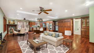 Living room with a skylight, dark hardwood / wood-style floors, and ceiling fan