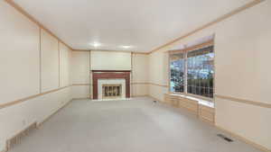 Unfurnished living room with light carpet and ornamental molding