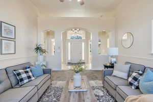 Carpeted living room featuring a towering ceiling, ceiling fan, and ornamental molding