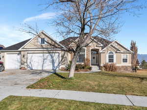 View of front of home with a mountain view, a garage, and a front lawn