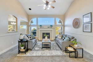 Living room with carpet floors, a fireplace, plenty of natural light, and high vaulted ceiling