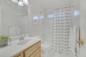 Full bathroom featuring tile patterned floors, vanity, toilet, and shower / tub combo with curtain