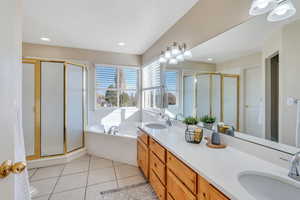 Primary Bathroom with tile floors, vanity, jetted tub and walk in shower