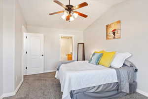 Carpeted bedroom with ensuite bath, ceiling fan, and vaulted ceiling