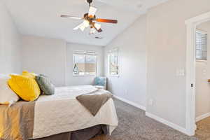 Carpeted bedroom with ceiling fan and lofted ceiling