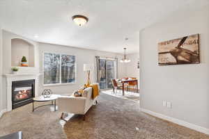 Living room featuring carpet, a chandelier, and a textured ceiling