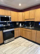 Kitchen with light hardwood / wood-style floors, sink, stainless steel appliances, and tasteful backsplash