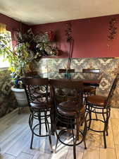 Dining room featuring light wood-type flooring, a textured ceiling, and bar