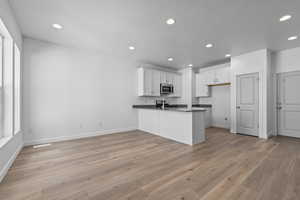 Kitchen featuring kitchen peninsula, white cabinetry, sink, and light hardwood / wood-style floors