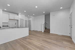 Kitchen with white cabinets, a textured ceiling, light hardwood / wood-style flooring, and sink