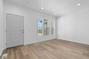 Unfurnished room featuring light hardwood / wood-style floors and a textured ceiling