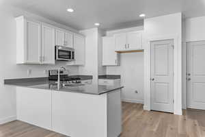 Kitchen featuring white cabinets, stainless steel appliances, kitchen peninsula, and light hardwood / wood-style floors