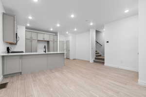 Kitchen featuring kitchen peninsula, gray cabinets, light hardwood / wood-style flooring, and range