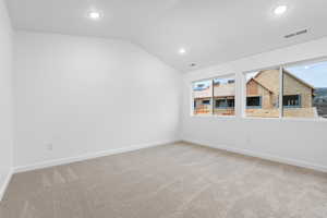 Carpeted empty room featuring lofted ceiling