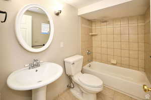 Full bathroom with tile patterned flooring, toilet, tiled shower / bath, and sink