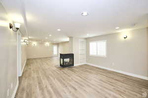 Basement featuring a multi sided fireplace and light hardwood / wood-style floors