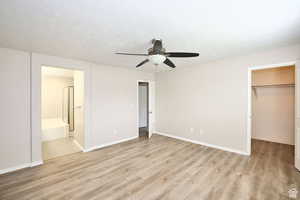 Unfurnished bedroom featuring ensuite bath, a spacious closet, ceiling fan, light hardwood / wood-style flooring, and a closet