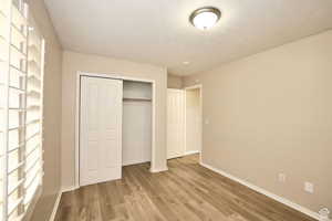 Unfurnished bedroom with hardwood / wood-style floors, a textured ceiling, and a closet