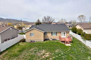 Back of house with a deck with mountain view and a yard