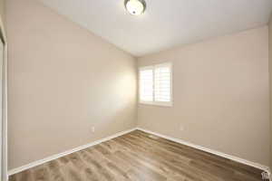 Spare room featuring wood-type flooring and vaulted ceiling