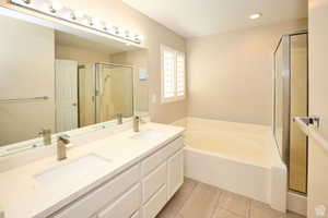 Bathroom featuring tile patterned floors, vanity, and plus walk in shower