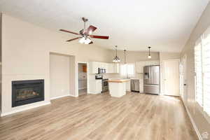 Kitchen featuring white cabinets, appliances with stainless steel finishes, a center island, and a wealth of natural light