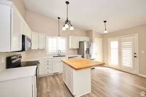 Kitchen featuring a kitchen island, white cabinetry, appliances with stainless steel finishes, and wooden counters