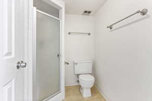 Bathroom with toilet, tile patterned floors, and a shower with shower door