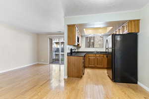 Kitchen with appliances with stainless steel finishes, light wood-type flooring, ornamental molding, and sink