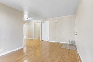 Unfurnished room with light hardwood / wood-style flooring and ornamental molding